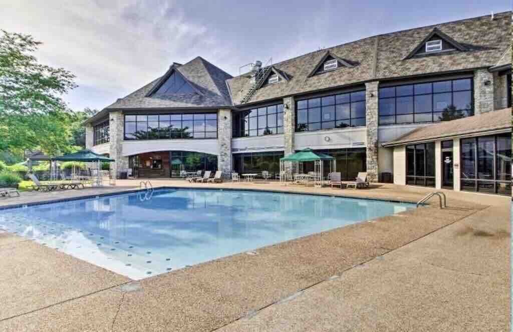 A large building with a swimming pool, outdoor seating, and a covered patio area.