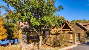 Une rangée de cabanes en bois, dotées de fondations en pierre, un mur de pierre et un arbre devant.