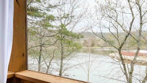 Un balcon en bois offrant une vue sur un lac et des arbres.