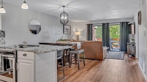 A modern kitchen with a central island, a dining area with a sofa, and a view of the outdoors through large windows. - Renovated Luxury! Indoor and Outdoor Pools! (Branson)