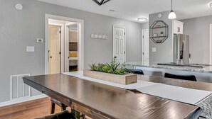 A modern kitchen with a built-in refrigerator, a dining table with a bench, and a hanging light fixture. - Renovated Luxury! Indoor and Outdoor Pools! (Branson)