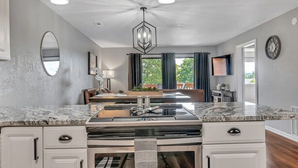 A modern kitchen with a marble countertop, white cabinets, and pendant lighting. - Renovated Luxury! Indoor and Outdoor Pools! (Branson)