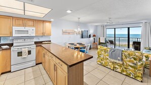 A modern kitchen with a central island, wooden cabinets, and a view of the ocean through large windows. - Oceanfront Condo Located in Paradise on S. Hutchinson Island/Stuart 
 (Stuart)