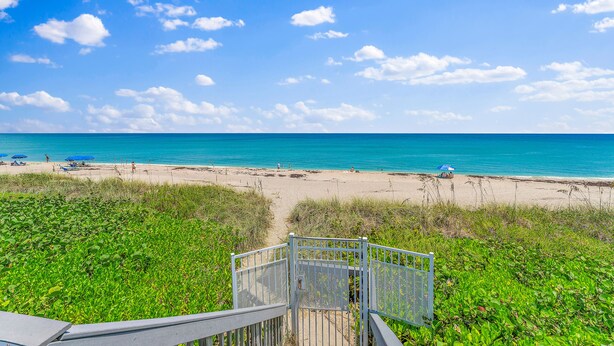 A beach view with a metal staircase leading down to the sand, surrounded by green vegetation. - Oceanfront Condo Located in Paradise on S. Hutchinson Island/Stuart 
 (Stuart)