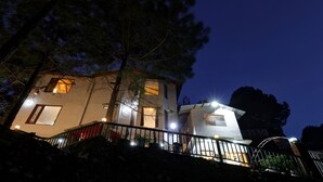 A two-story building with a staircase leading to the entrance, surrounded by trees. - Treebo Vista Lago With Lake View (Nainital)