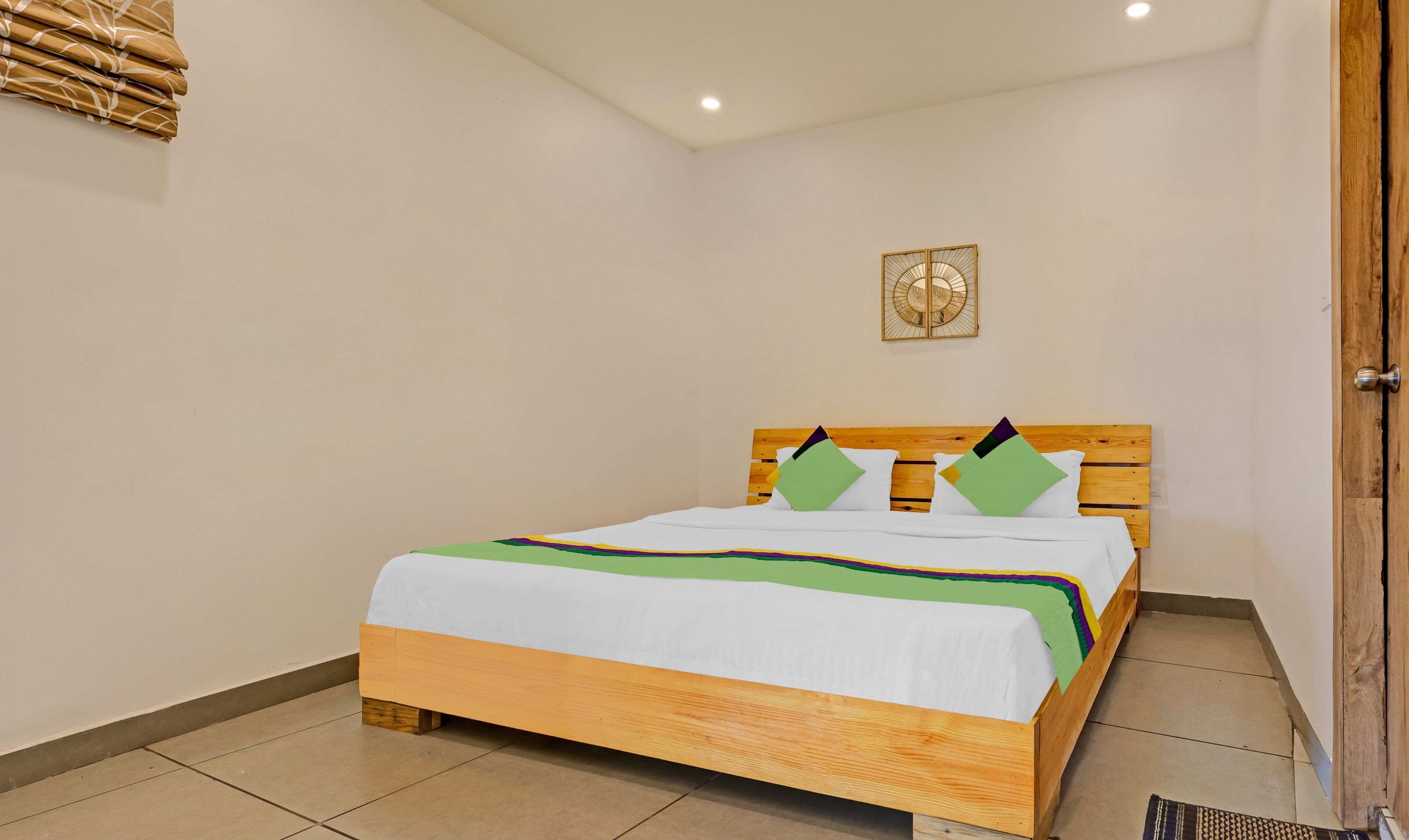 Cama bem arrumada com cabeceira de madeira, roupa de cama branca e almofadas coloridas.