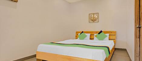 Cama bem arrumada com cabeceira de madeira, roupa de cama branca e almofadas coloridas.