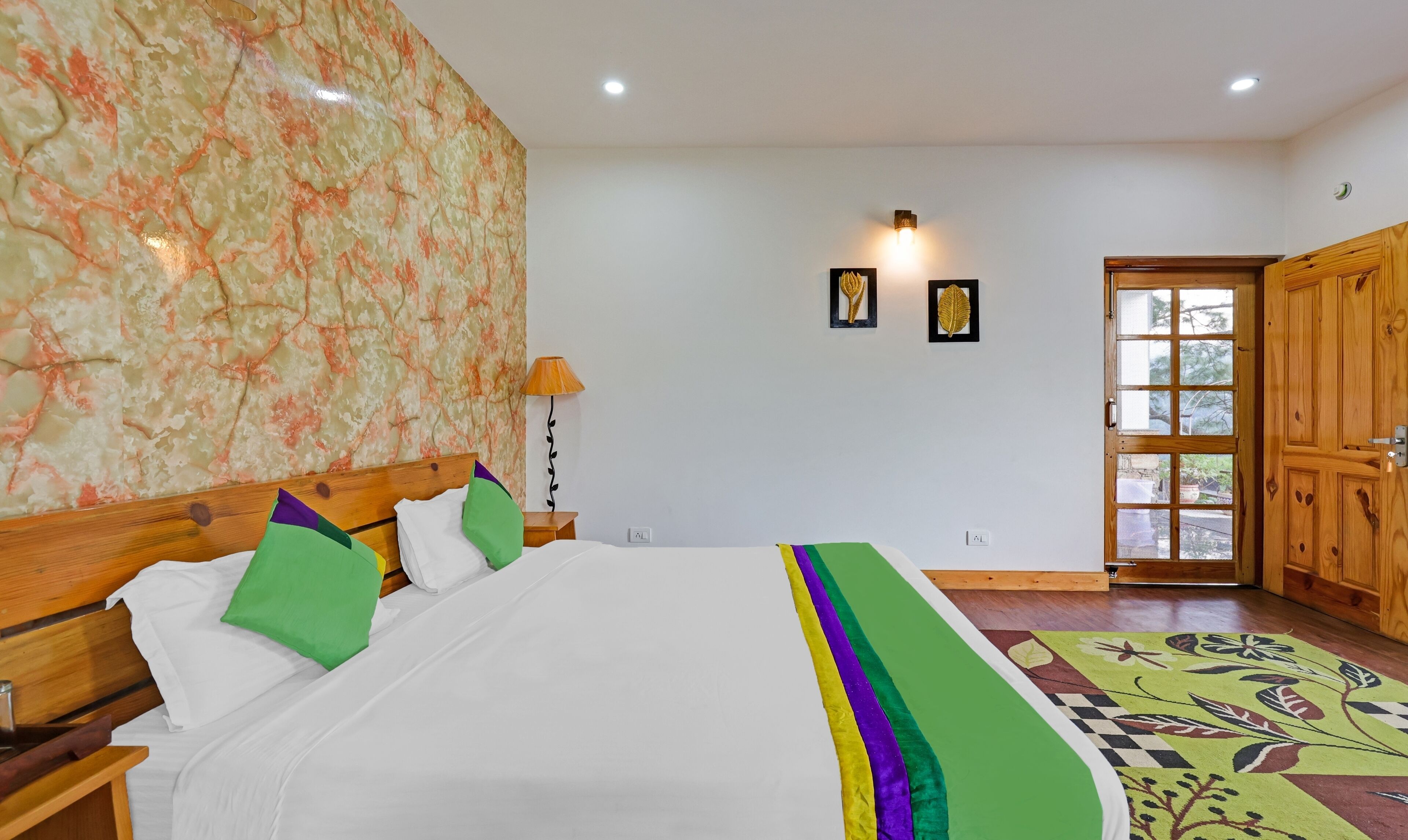 Una camera da letto con un letto di legno, carta da parati a motivi floreali, una porta con pannelli di vetro e un tappeto decorato.