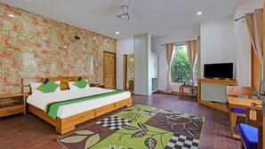 A bedroom with a bed, wooden nightstands, a TV, a desk, and a window with curtains. - Treebo Vista Lago With Lake View (Nainital)
