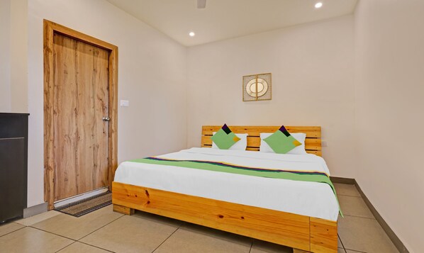 A room with a wooden bed, a door, and a wall-mounted light fixture. - Treebo Vista Lago With Lake View (Nainital)