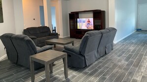 Una sala de estar con dos sofás grises, una mesa de centro de madera y un televisor sobre un mueble de madera.