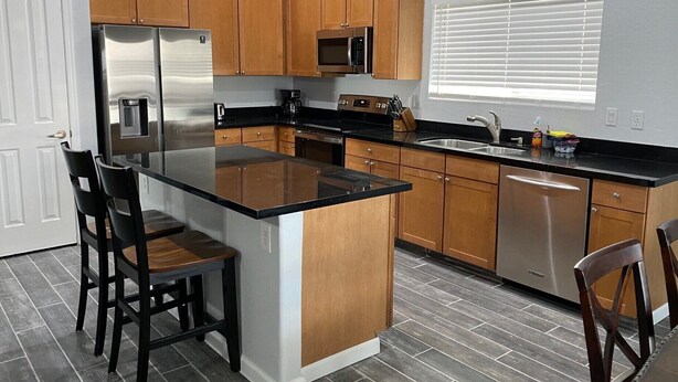 Una cocina con gabinetes de madera, un refrigerador de acero inoxidable, un microondas y un lavavajillas.