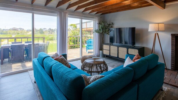 Ein großzügiger Wohnbereich mit einer großen Couch, einem Fernseher und Blick ins Freie.