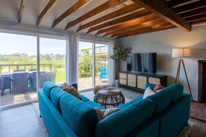 A spacious living area with a large sofa, a television, and a view of the outdoors.