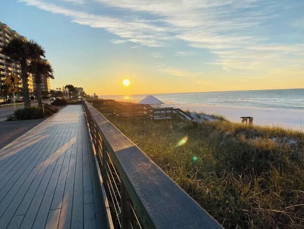 A wooden boardwalk leading to a beach with a sunset in the background. - Close to beach & Steps to pool = AMAZING VACATION! (Miramar Beach)