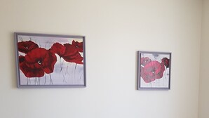 Ett sovrum med en säng, två inramade konstverk, ett sängbord med en lampa och ett litet bord vid sängen.
