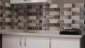 Una cocina con armarios blancos, una campana extractora de acero inoxidable y un salpicadero de azulejos.