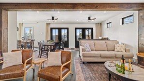 A spacious living area with a sofa, chairs, a coffee table, and a dining area with a table and chairs. - Spacious Winter Retreat w/ Hot Tub, Games, Fire Pit & Scenic Hilltop Views! (Thompson)