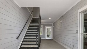 A staircase leading to a door, with grey siding walls and a concrete floor.