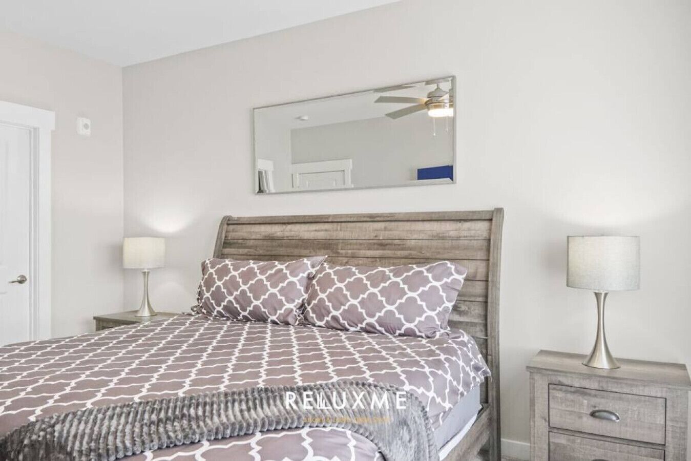Une chambre à coucher avec une tête de lit en bois, une literie à motifs, un miroir et des lampes de chevet.