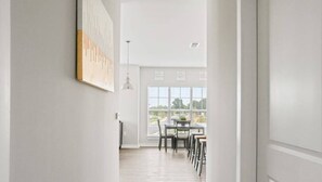 Un intérieur moderne avec un coin repas, des murs blancs et une vue dégagée grâce à de grandes fenêtres.