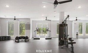 Une salle de sport moderne équipée de tapis de course, d’appareils de musculation et de ventilateurs de plafond.