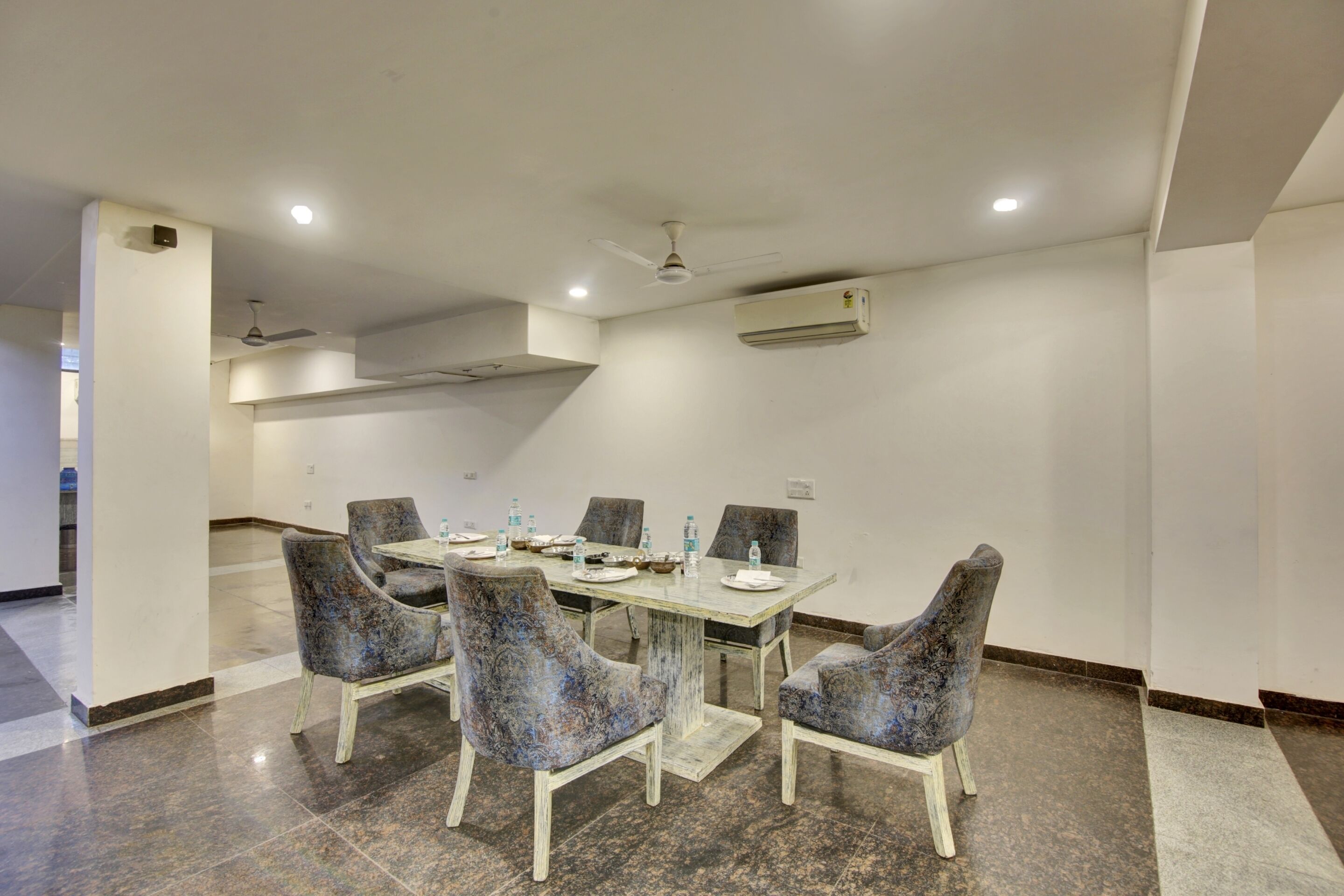 A conference room with a rectangular table, six chairs, and a ceiling fan.