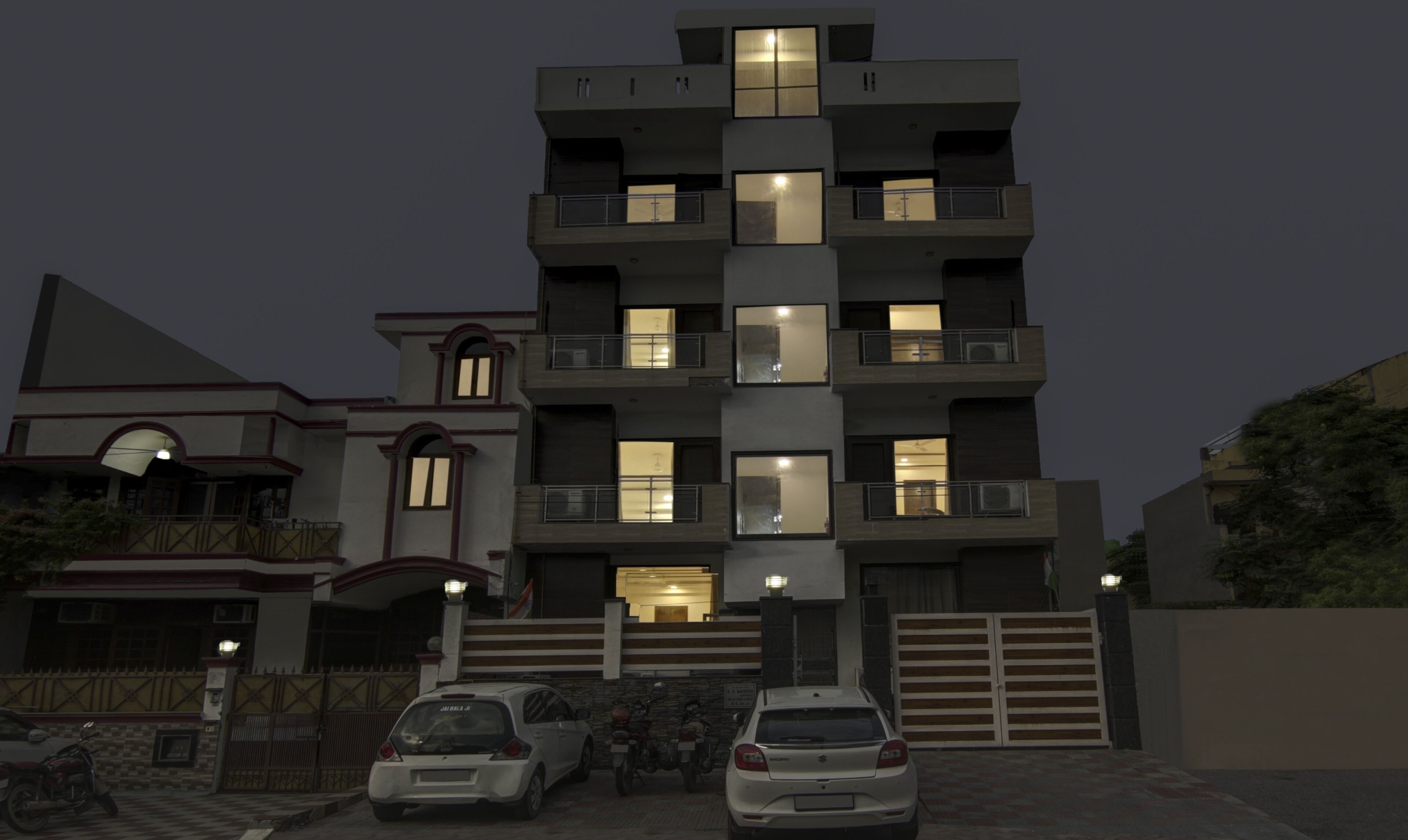 Un edificio residencial de varios pisos con balcones y ventanas iluminadas.