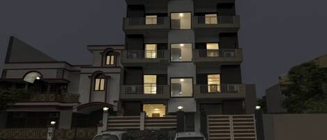 Un edificio residencial de varios pisos con balcones y ventanas iluminadas.
