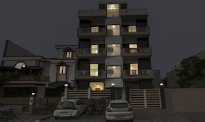 A multi-story residential building with balconies and illuminated windows. - Treebo Apple Pie (Noida)