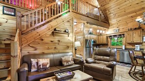 Ein Interieur einer Holzhütte mit einer Holztreppe, Ledermöbeln, einer Küchenzeile und einem Schild, das anzeigt, dass die Hütte 3 Kilometer entfernt ist.