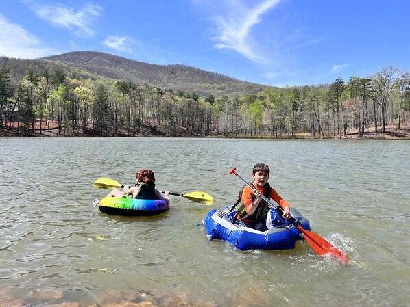 Two people in inflatable rafts on a calm lake surrounded by trees and hills. - Fisherman paradise on private lake 5 minutes from Helen (Sautee Nacoochee)