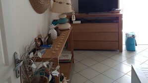 A room with a television, a wooden table, a wicker mirror, and a wicker basket.