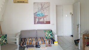 A spacious living area with a white sofa, a coffee table, and a painting on the wall.
