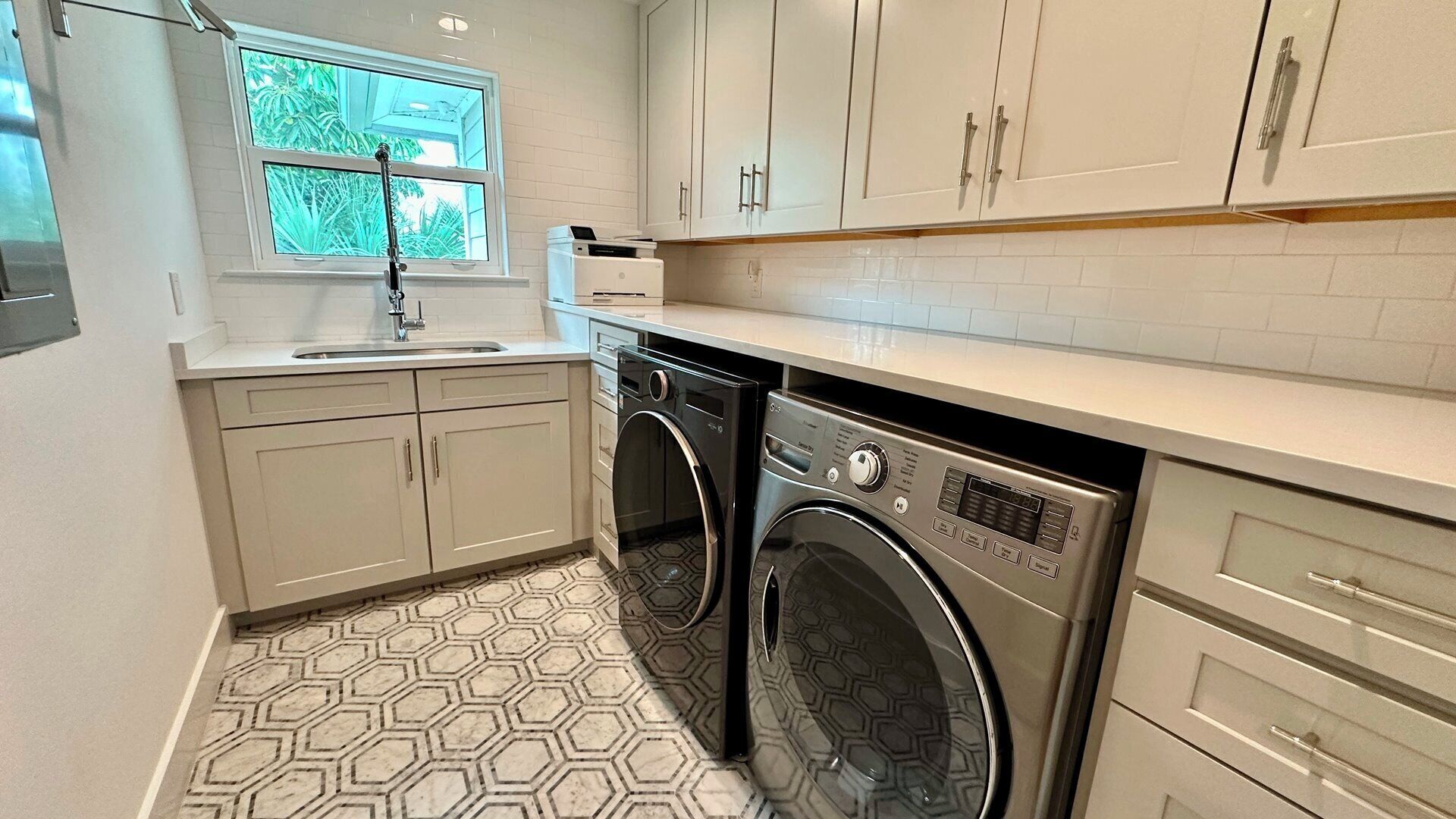 A compact kitchen with a washing machine, a sink, and cabinets.