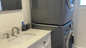 A compact bathroom with a modern sink, a built-in washing machine, and a mirror. - beautiful Modern apartment, close to everything ! (Hicksville)