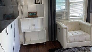 A modern living room with a white entertainment unit, a beige sofa, and a large window with blinds. - beautiful Modern apartment, close to everything ! (Hicksville)