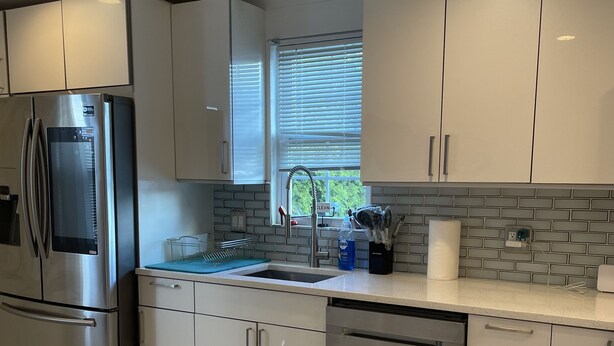 A modern kitchen with stainless steel appliances, white cabinetry, and a tiled backsplash. - beautiful Modern apartment, close to everything ! (Hicksville)