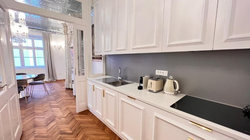 Una cocina moderna con armarios blancos, encimera negra y estufa integrada.