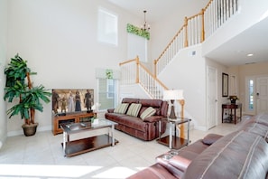 Relax in this inviting living room with a high ceiling, comfortable sofa, and a beautiful painting on the wall.