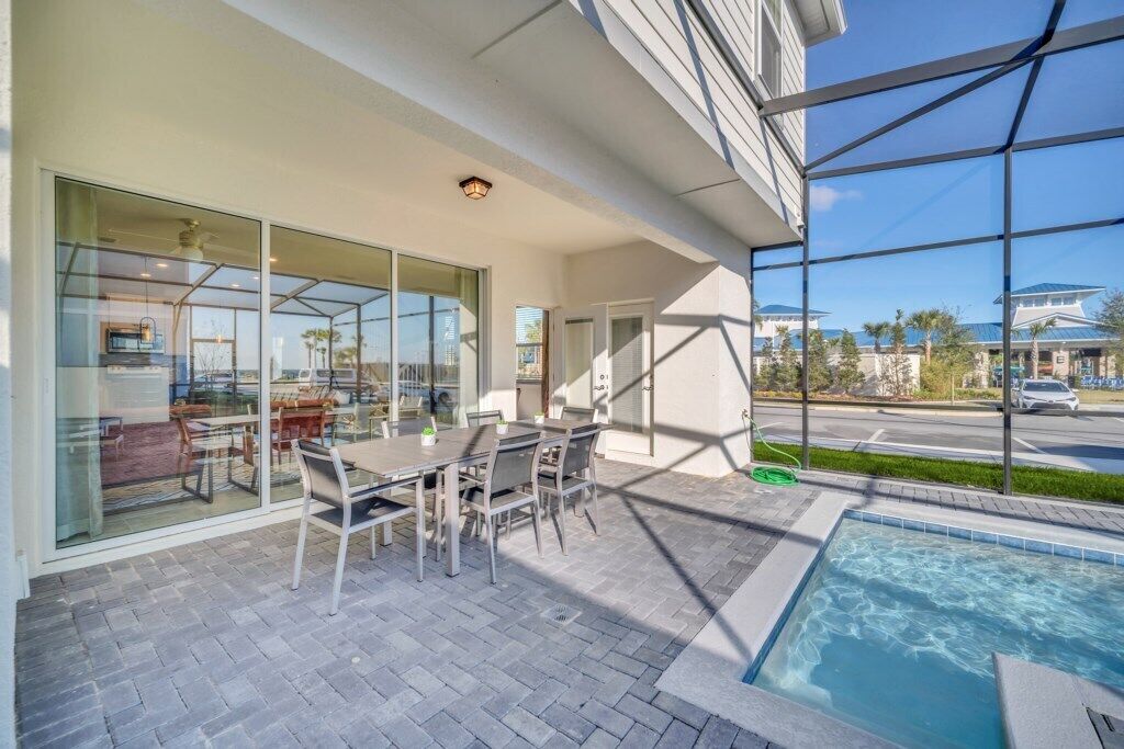 A modern outdoor patio with a pool, glass walls, and a view of a street and buildings in the background.