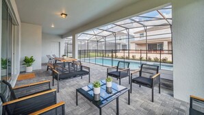 A covered patio area with outdoor furniture, a pool, and a view of neighboring houses. - The Ultimate New 8  Bedroom 6  Bathroom Resort Home (Davenport)
