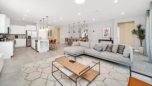 A modern living room with a sectional sofa, a coffee table, and a dining area with chairs. - The Ultimate New 8  Bedroom 6  Bathroom Resort Home (Davenport)