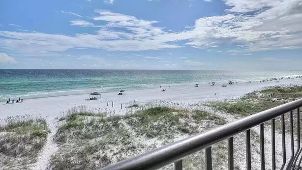 A beach with a clear sky, sandy shore, and a few umbrellas.