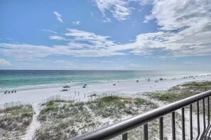A beach with a clear sky, sandy shore, and a few umbrellas.