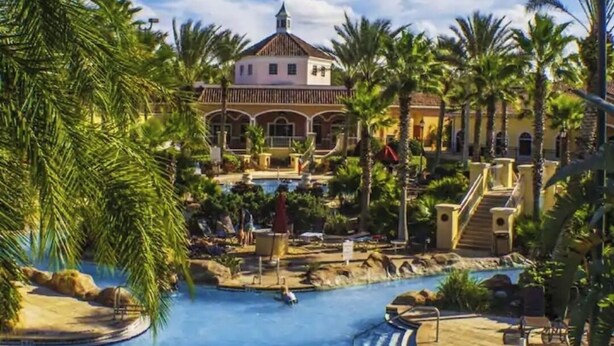 Um resort com piscina, palmeiras e um edifício com cobertura em cúpula.