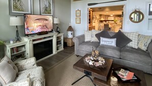 Ett vardagsrum med en tv, en soffa, ett soffbord och dekorativa kuddar.