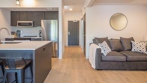 A modern kitchen with a central island, a dining area with bar stools, and a living room with a sofa and decorative pillows. - Modern condo in Downtown Bozeman w/private balcony, private parking, and AC - SOBO Urban Oasis (Bozeman)