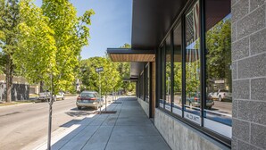 A sidewalk adjacent to a building with large windows and a tree in the foreground. - Modern condo in Downtown Bozeman w/private balcony, private parking, and AC - SOBO Urban Oasis (Bozeman)