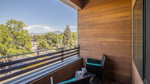 A balcony with wooden walls, a view of a cityscape, and a table with chairs. - Modern condo in Downtown Bozeman w/private balcony, private parking, and AC - SOBO Urban Oasis (Bozeman)